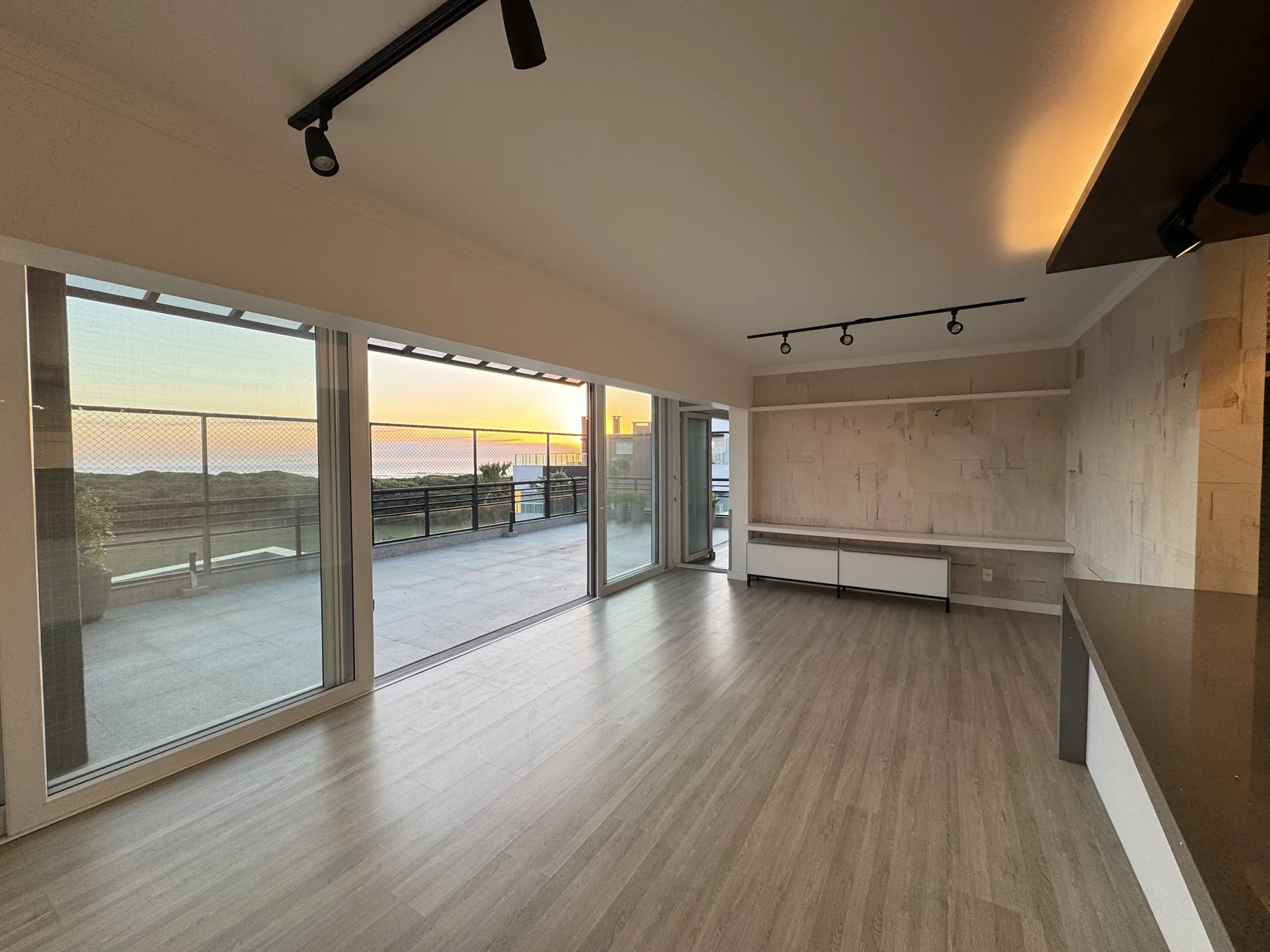 Sala de estar aberta pro terraço, com vista pro mar
